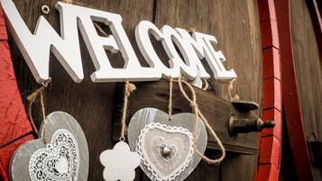 A wooden door with a 'WELCOME' sign and decorative heart-shaped ornaments.