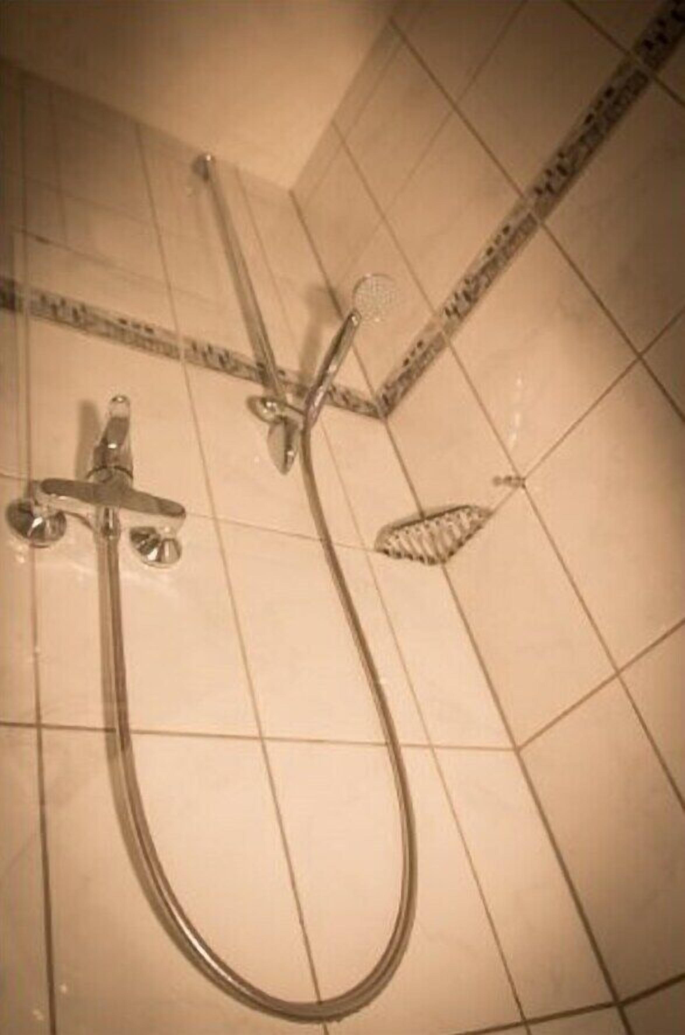 A shower with a handheld showerhead and a fixed wall-mounted showerhead.