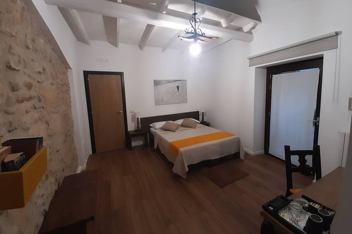 Un dormitorio con cama, mesita de noche y lámpara colgante.