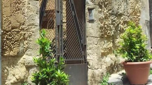 Un edificio de piedra con una reja de hierro forjado y un letrero que dice "B&B Antica Nostra".