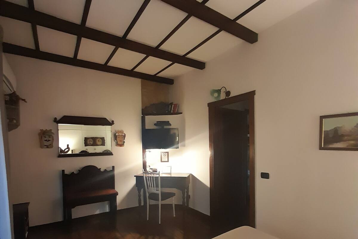 Una habitación con cama, un escritorio con silla, una televisión y una puerta.