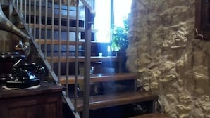 Una escalera con paredes de piedra y un escritorio de madera con un teléfono.
