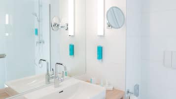 A modern bathroom with a large mirror, a sink, and a shower.