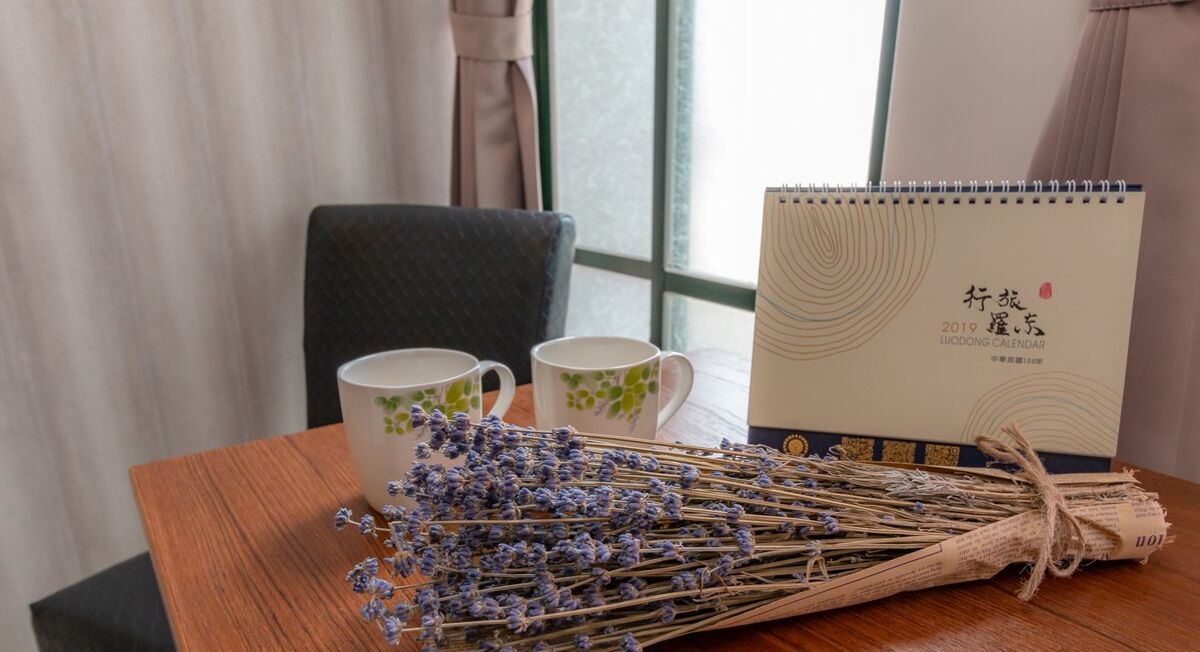 A table with a calendar, two cups, and a bundle of lavender.