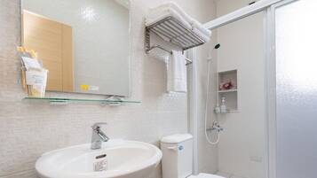 Ein Badezimmer mit Waschbecken, Spiegel, Handtuchhalter, Dusche und Toilette.