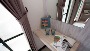 A room with a wooden table, two blue glasses, a framed picture, and a poster. - Jia-Jia Business Hotel (Luodong)