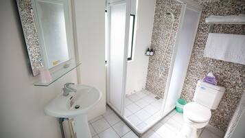 Un baño con cabina de ducha de vidrio, un lavabo y un inodoro.