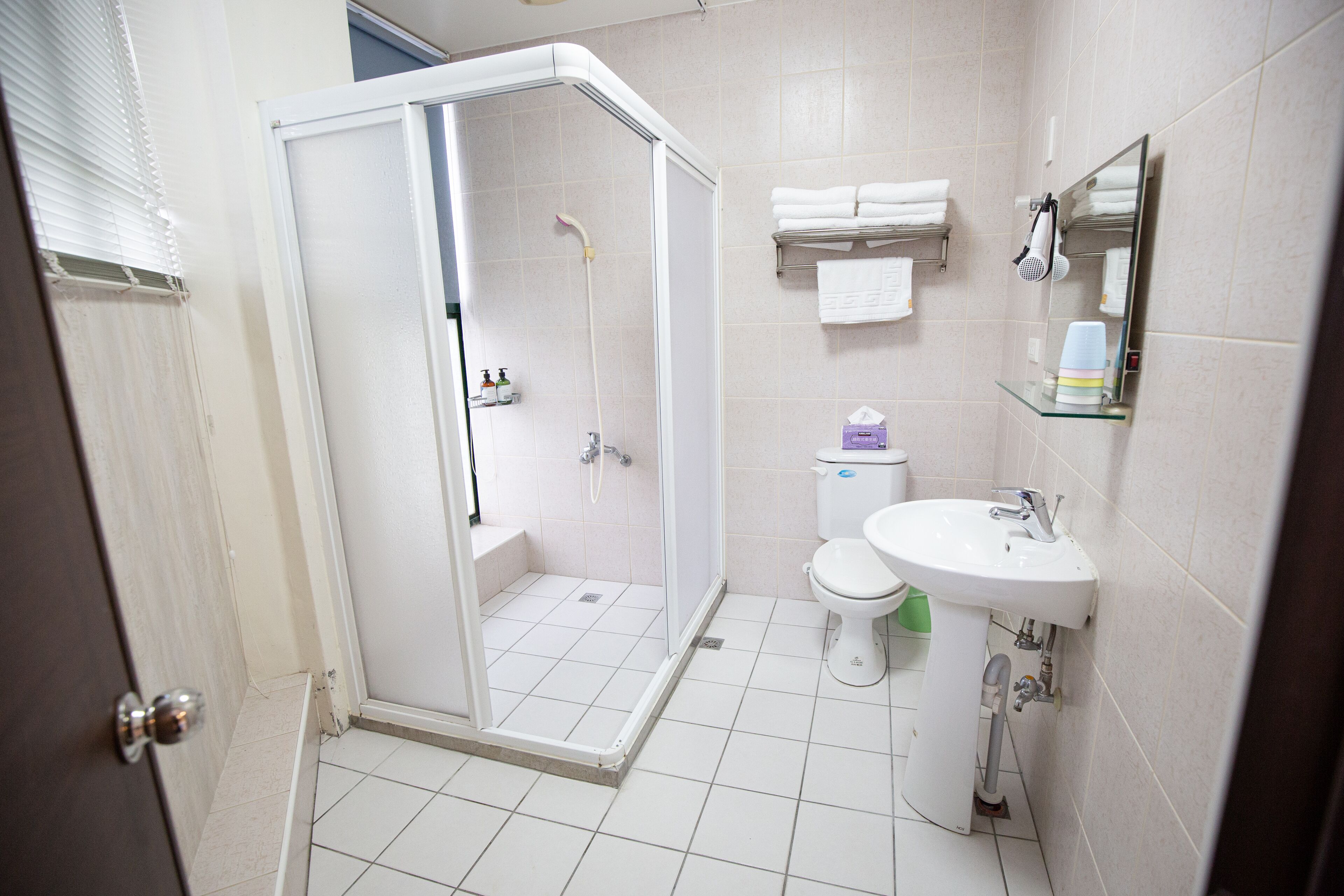 A bathroom with a glass-enclosed shower, a toilet, a sink, and a mirror.