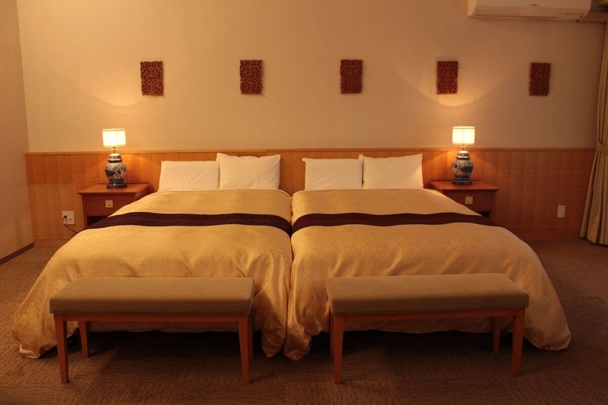 Een hotelkamer met een tweepersoonsbed en twee nachtkastjes, elk met een lamp.