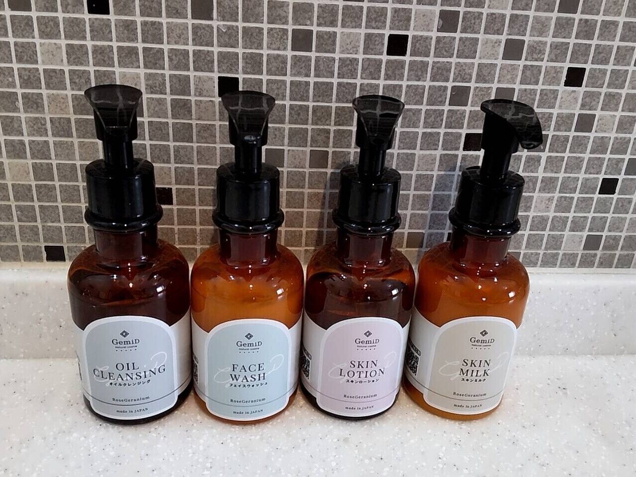 Quatre flacons de produits de soins pour la peau sont posés sur un comptoir.