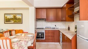 Una cocina compacta con gabinetes de madera, estufa a gas, horno empotrado y lavavajillas.