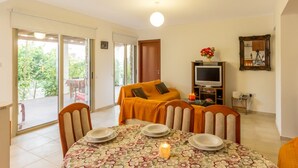 Una sala de estar acogedora con un sofá, televisor y mesa de comedor preparada para cuatro personas.