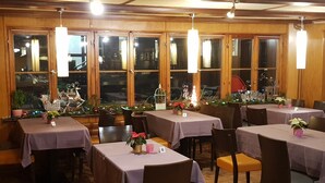 A restaurant with multiple tables, each covered with a tablecloth, and chairs around them. - Antico mulino (Todtmoos)