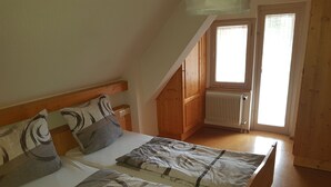 A bedroom with two beds, wooden headboards, and a window with a view. - Antico mulino (Todtmoos)