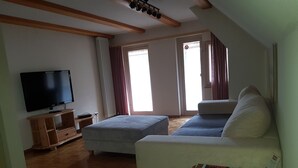 A living room with a flat-screen TV, a wooden entertainment unit, a sofa, and a table with magazines. - Antico mulino (Todtmoos)