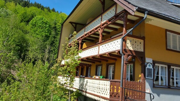 A two-story building with a balcony, surrounded by lush greenery. - Antico mulino (Todtmoos)