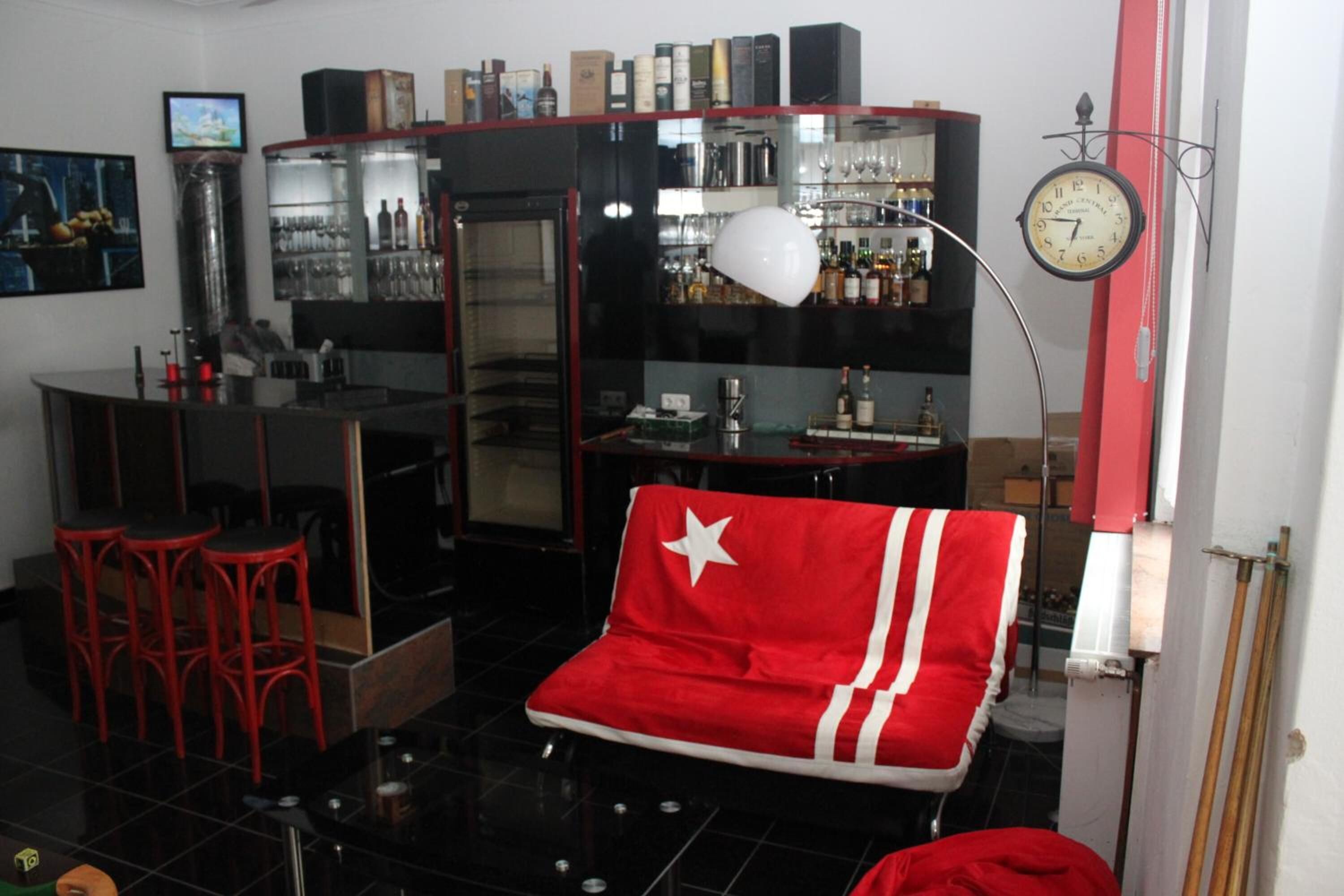 Un espace bar avec des tabourets, un comptoir et des étagères remplies de bouteilles et de verres.