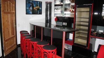 A bar area with red stools, a refrigerator, and a wine rack.
