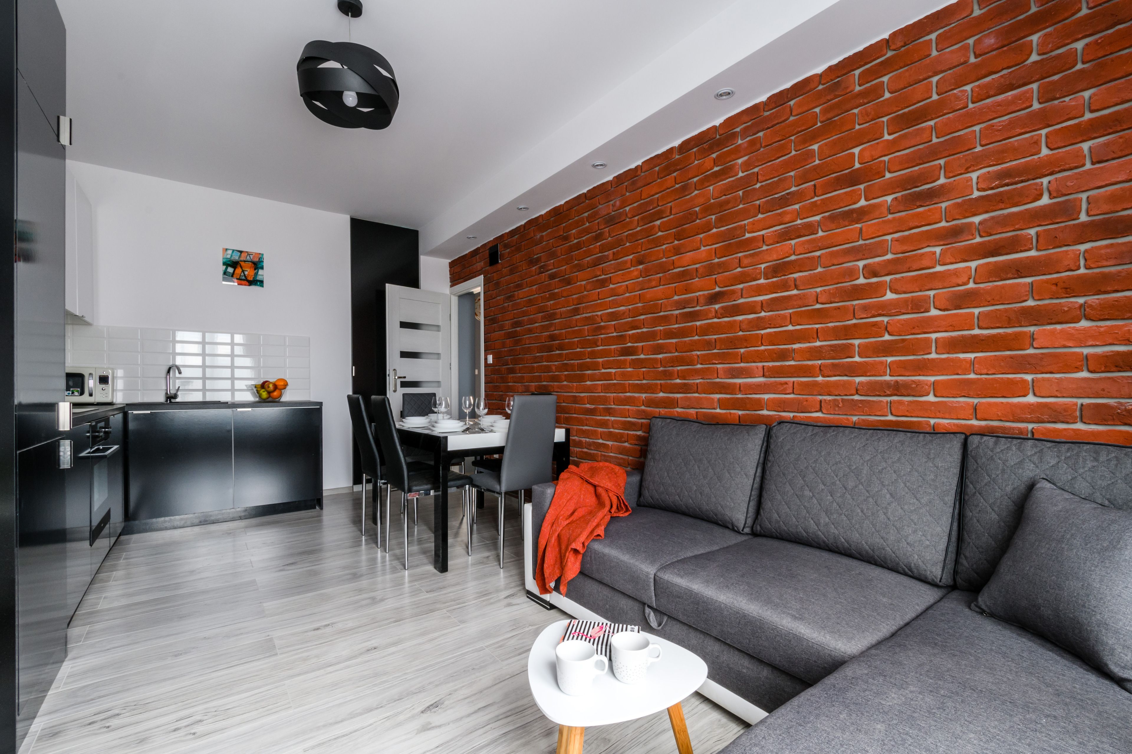 A modern living space with a grey sofa, a small white table, and a brick wall.