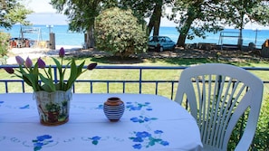 Une table recouverte d’une nappe à motifs floraux, une chaise blanche et un vase rempli de fleurs.