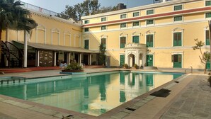 A pool area with a building featuring multiple windows and a staircase. - Yellow Durbar Apartment and Lounge (Lalitpur)