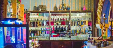 A bar with shelves of bottles and glasses, a vintage radio, and a hookah.