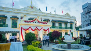 A traditional building with a white facade, green windows, and a central entrance with red drapery. - Yellow Durbar Apartment and Lounge (Lalitpur)