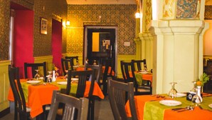 A restaurant interior with wooden chairs and tables, each covered with orange tablecloths. - Yellow Durbar Apartment and Lounge (Lalitpur)