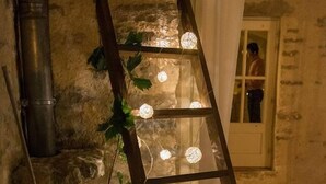 Una escalera de madera con luces de cuerda frente a una pared de piedra.