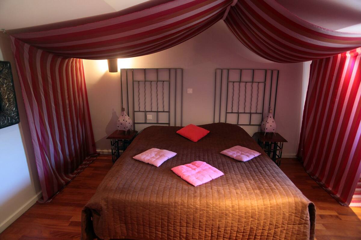 Een slaapkamer met een groot bed, gestreepte gordijnen en twee wandlampen.