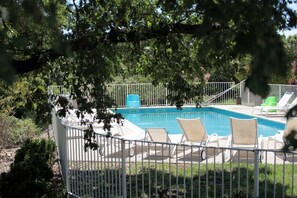 A swimming pool with lounge chairs and a fenced area.