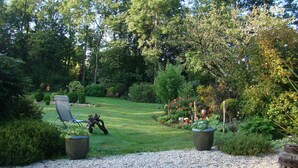 A garden with a lawn, a chair, and potted plants. - Chambres d'hôtes La Bruyère (May-sur-Orne)