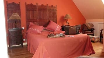 A bedroom with a large bed, two nightstands, a dresser, and a wooden headboard.
