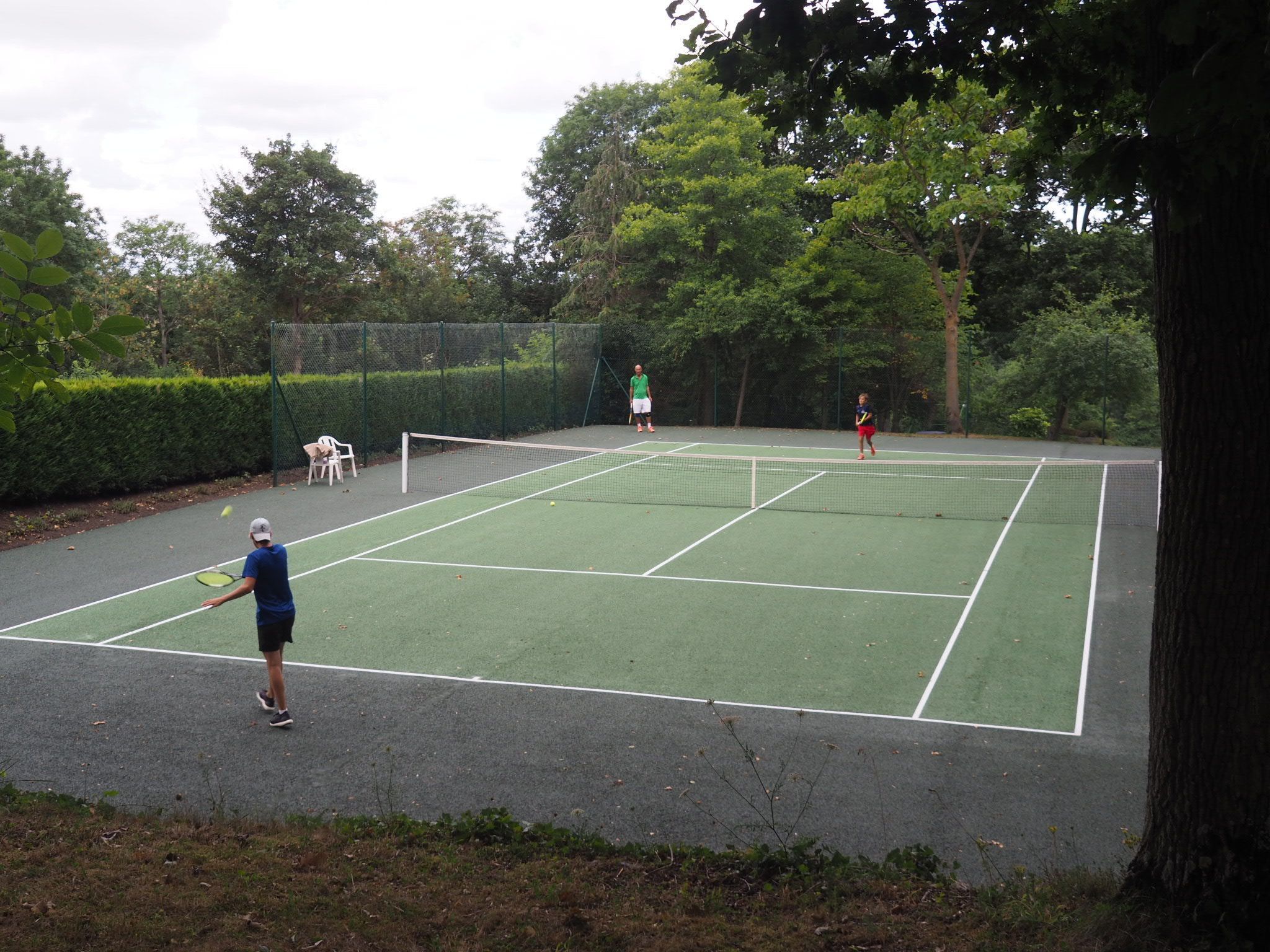 Un campo da tennis all'aperto circondato da alberi.