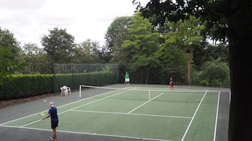 Un campo da tennis all'aperto circondato da alberi.