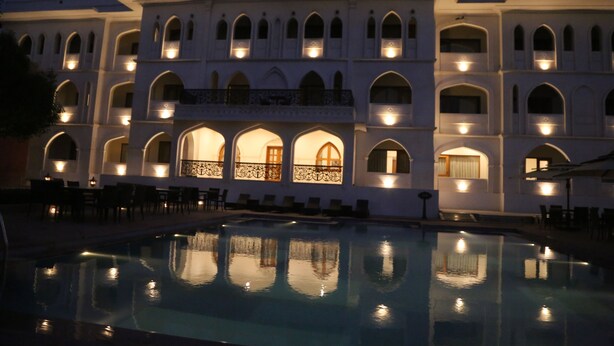 Un hôtel doté d’une piscine, de plusieurs balcons et d’un éclairage chaleureux.