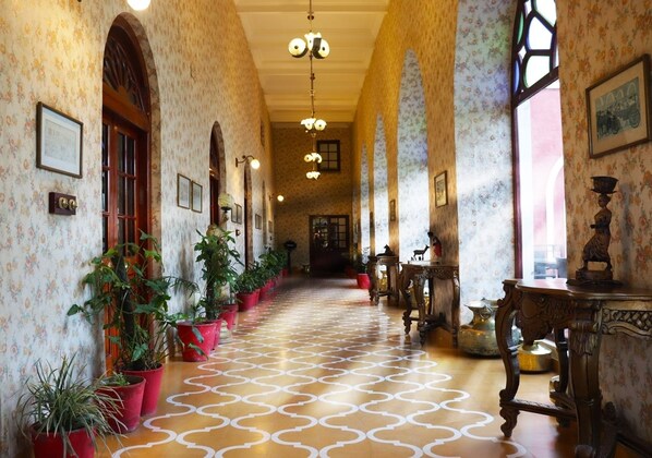 A hallway with patterned flooring, potted plants, and wooden furniture.
