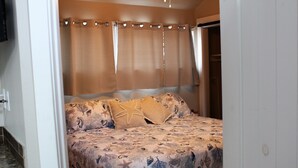 A bedroom with a bed, curtains, and a door.