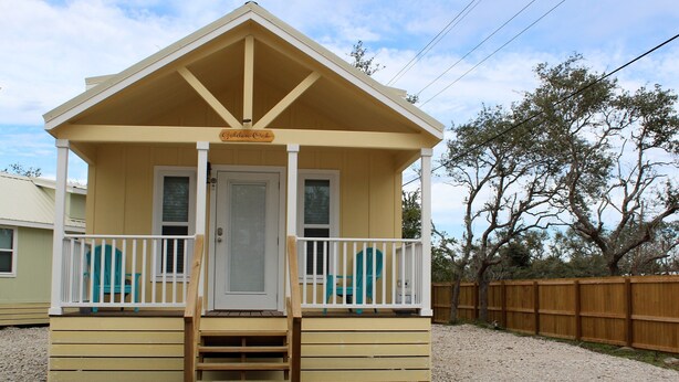 A small, single-story building with a front porch and a wooden deck.