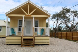 A small, single-story building with a front porch and a wooden deck.