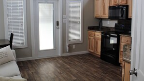A compact kitchen with wooden cabinets, a black refrigerator, and a stove.