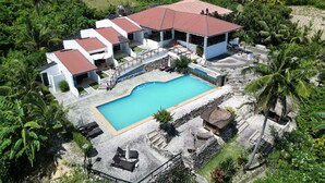 A resort with multiple buildings, a swimming pool, and lush greenery.