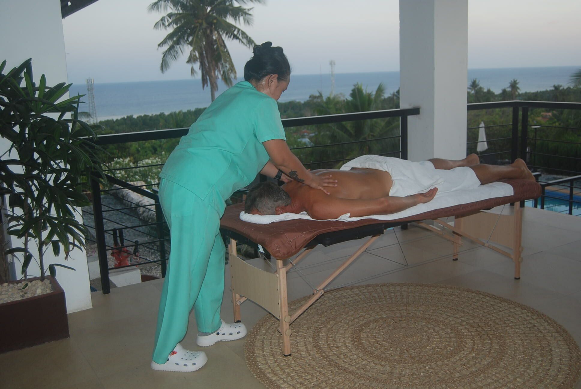 A massage therapy session on a balcony with a view of the ocean.