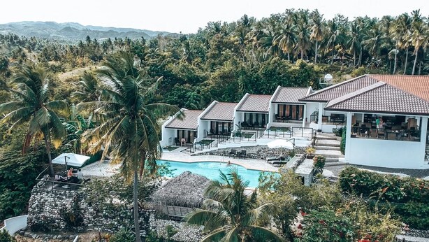 A resort with multiple villas, a swimming pool, and lush tropical vegetation.
