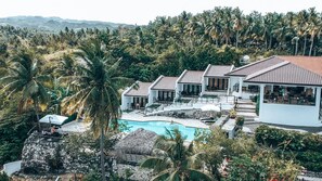 Un complexe hôtelier comprenant plusieurs villas, une piscine et une végétation tropicale luxuriante.