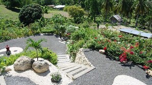 A landscaped garden with a gravel path, palm trees, and red flowers. - Panorama de Argao Boutique Resort (Argao)