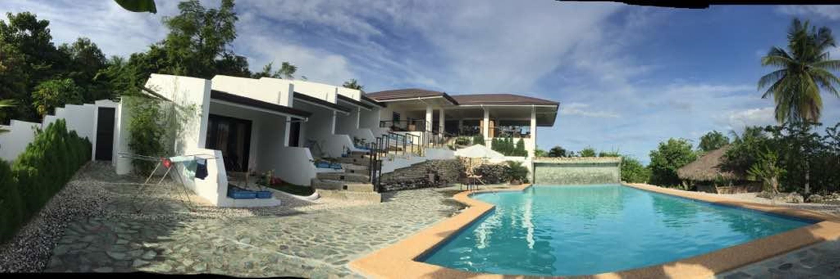 Una casa moderna con piscina, rodeada de vegetación tropical.