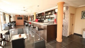 A restaurant with a bar area, high chairs, and a tiled floor. - Parigha Hotel (Accra)