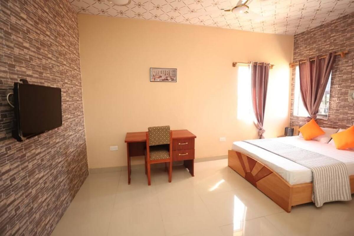 A bedroom with a bed, a desk, a chair, a television, and a picture on the wall.