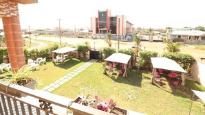 A courtyard with outdoor seating, a building in the background, and a view of the surrounding area. - Parigha Hotel (Accra)